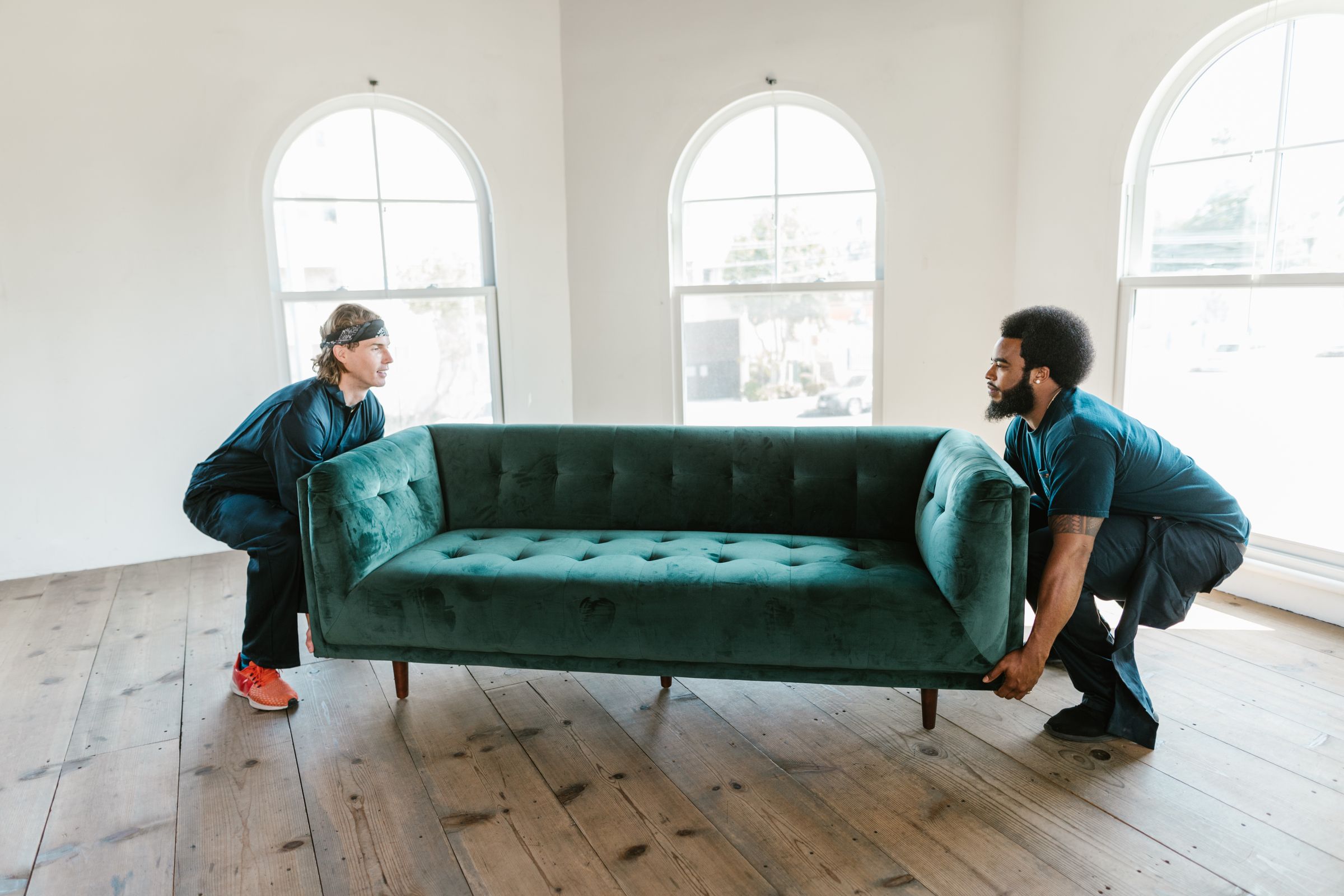 Two movers carrying a sofa in a home